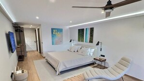 Une chambre moderne avec un lit, une chaise, un bureau et un ventilateur de plafond.