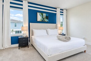 A bedroom with a large bed, two bedside tables, a window with curtains, and a painting on the wall. - 3BR Reunion Villa, Resort Pool Access (Four Corners)