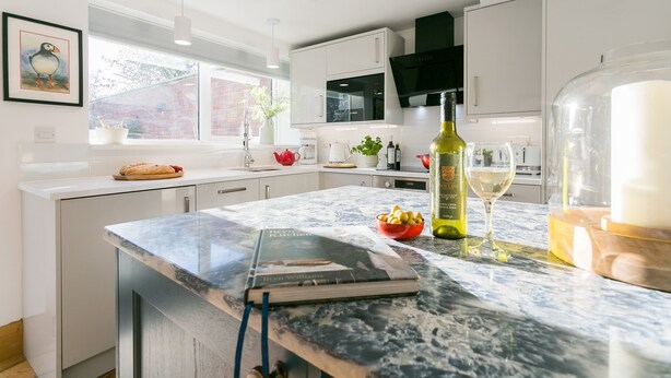 A modern kitchen with white cabinets, a marble countertop, a Bosch microwave, and a wine bottle. - Rutherglen - sleeps 4 guests  in 2 bedrooms (Beaumaris)