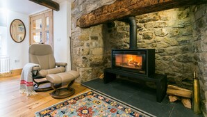 A cozy living room with a stone fireplace, a comfortable leather chair, and a colorful rug. - Rutherglen - sleeps 4 guests  in 2 bedrooms (Beaumaris)