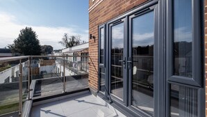 Ein modernes Gebäude mit großen Glasfenstern und einem Balkon mit Glasgeländer.