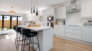 Eine moderne Küche mit weißen Schränken, einer großen Kücheninsel mit Barhocker und einem eingebauten Backofen.