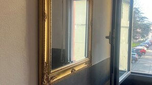 A room with a large mirror reflecting a window view of parked cars and a building. - Il Torrione - Cozy Independent House for 4, between History and Relaxation (Castel Bolognese)