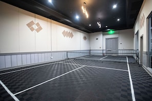 A tennis court with a net, walls with geometric patterns, and a door. - The Palms Destin 2103 (Destin)