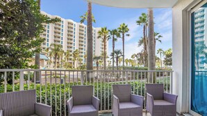 A balcony with wicker furniture and a view of palm trees and high-rise buildings. - The Palms Destin 2103 (Destin)