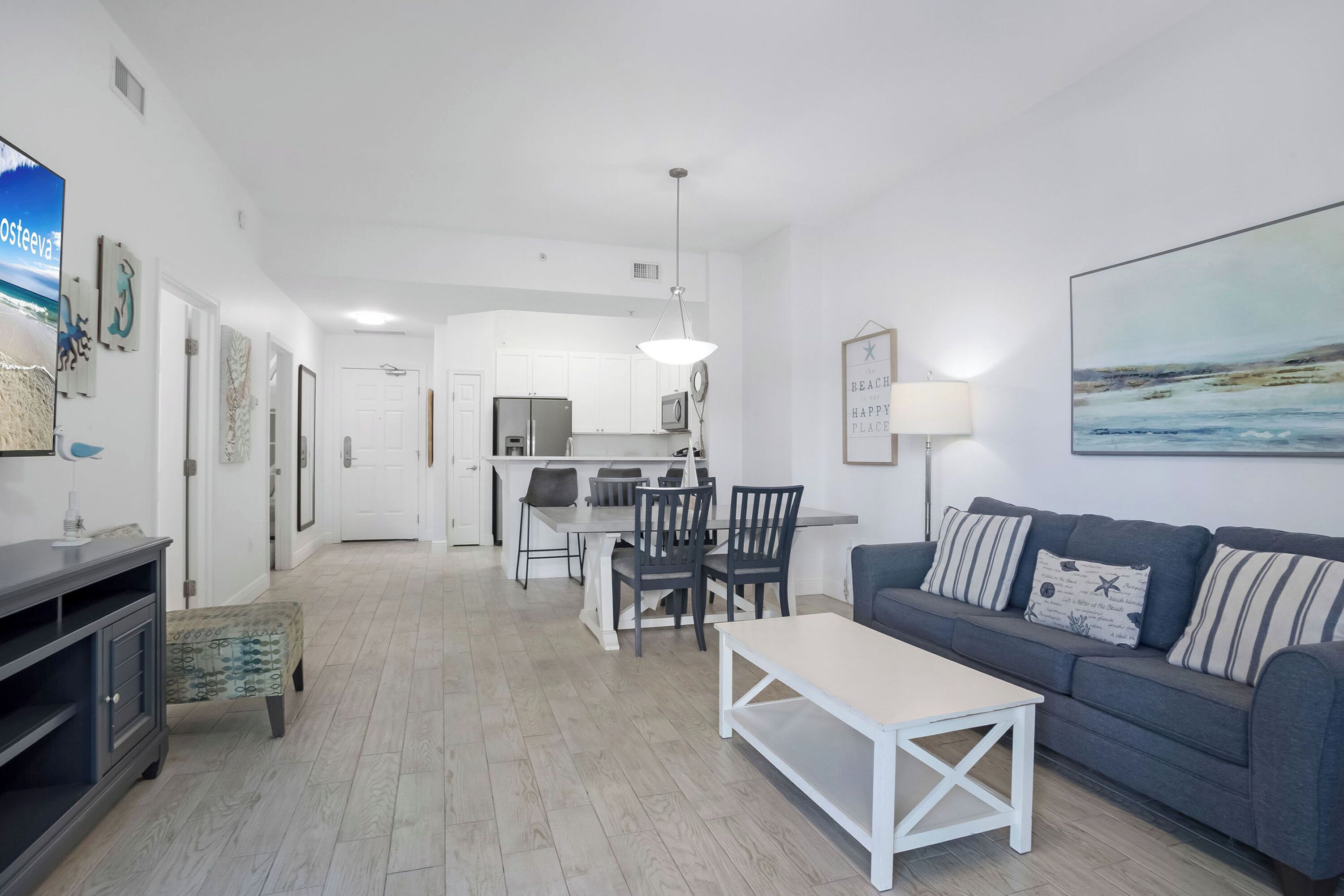 Una sala de estar moderna con un sofá gris, una mesa de centro y un comedor con sillas y una mesa.