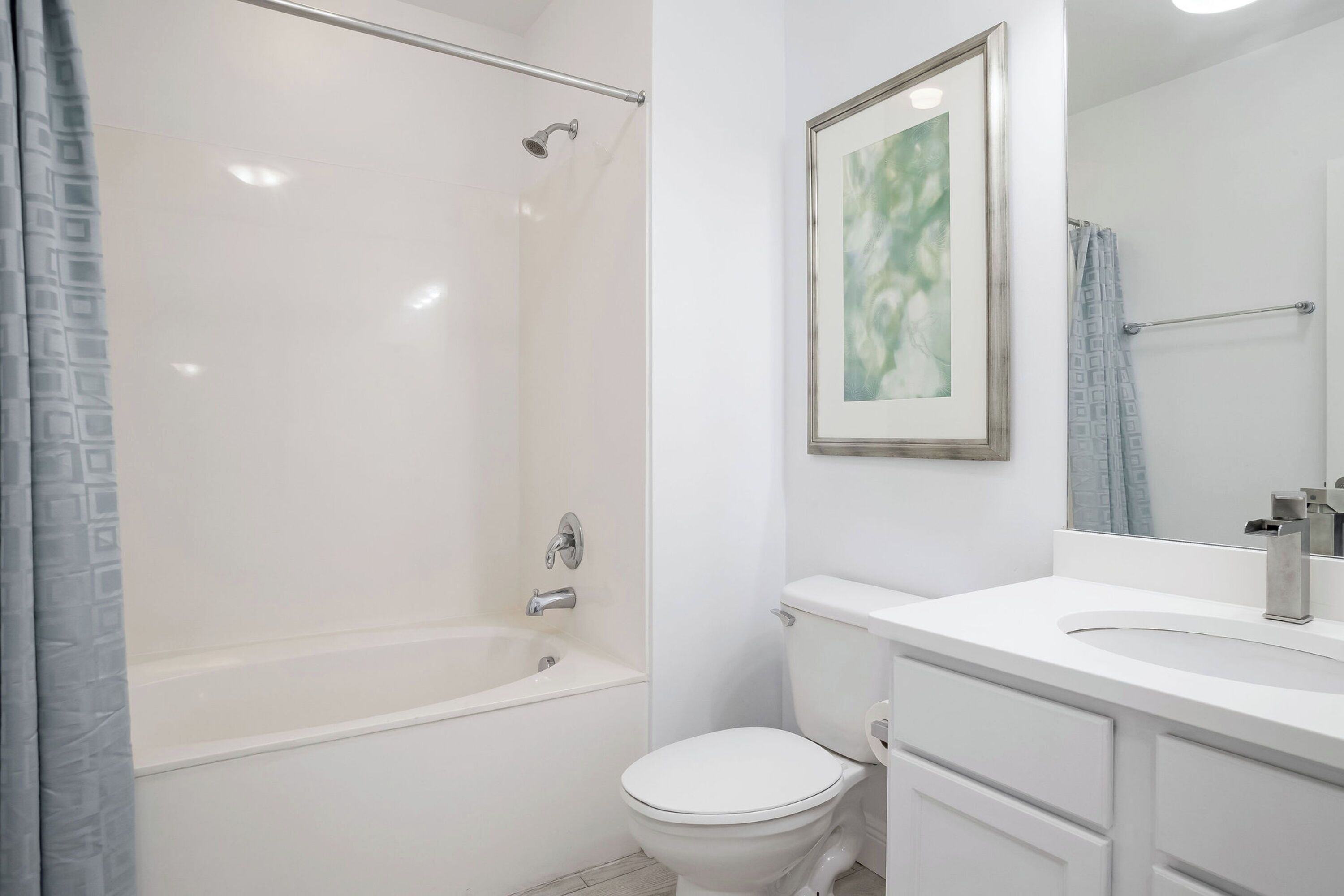 Un baño con bañera, inodoro y lavabo con espejo.