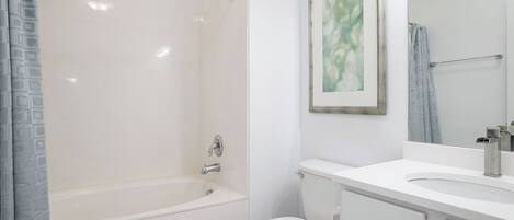 Un baño con bañera, inodoro y lavabo con espejo.