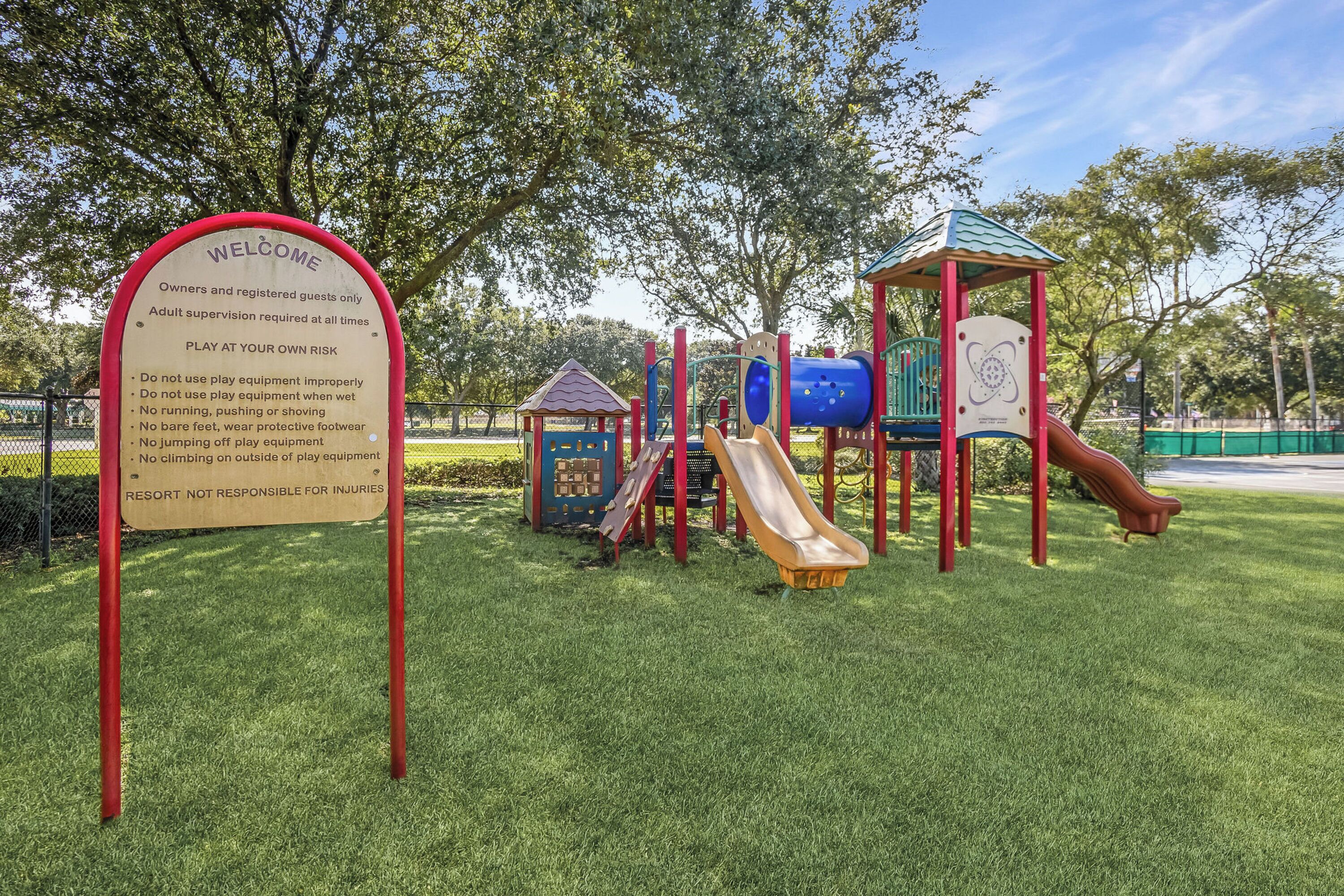 Un parque infantil con un tobogán, estructuras para escalar y una zona vallada.