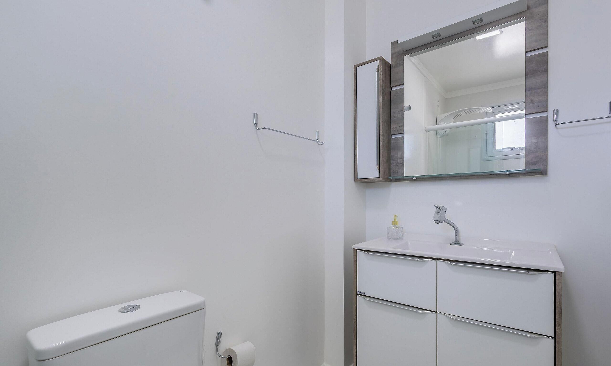 Une petite salle de bain propre, équipée de toilettes, d’un lavabo et d’un miroir.