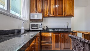 A kitchen with wooden cabinets, a microwave, a toaster, and a kettle. - Apt w/ BBQ & Balcony, 450m From the Beach Sit1202 (Itapema)