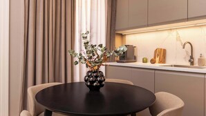 Een moderne keuken met een centraal eiland, hanglampen en een eethoek met een ronde tafel en stoelen.