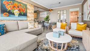 Ein Wohnzimmer mit einer Couch, Sesseln, einem Couchtisch und einem Blumenbild.