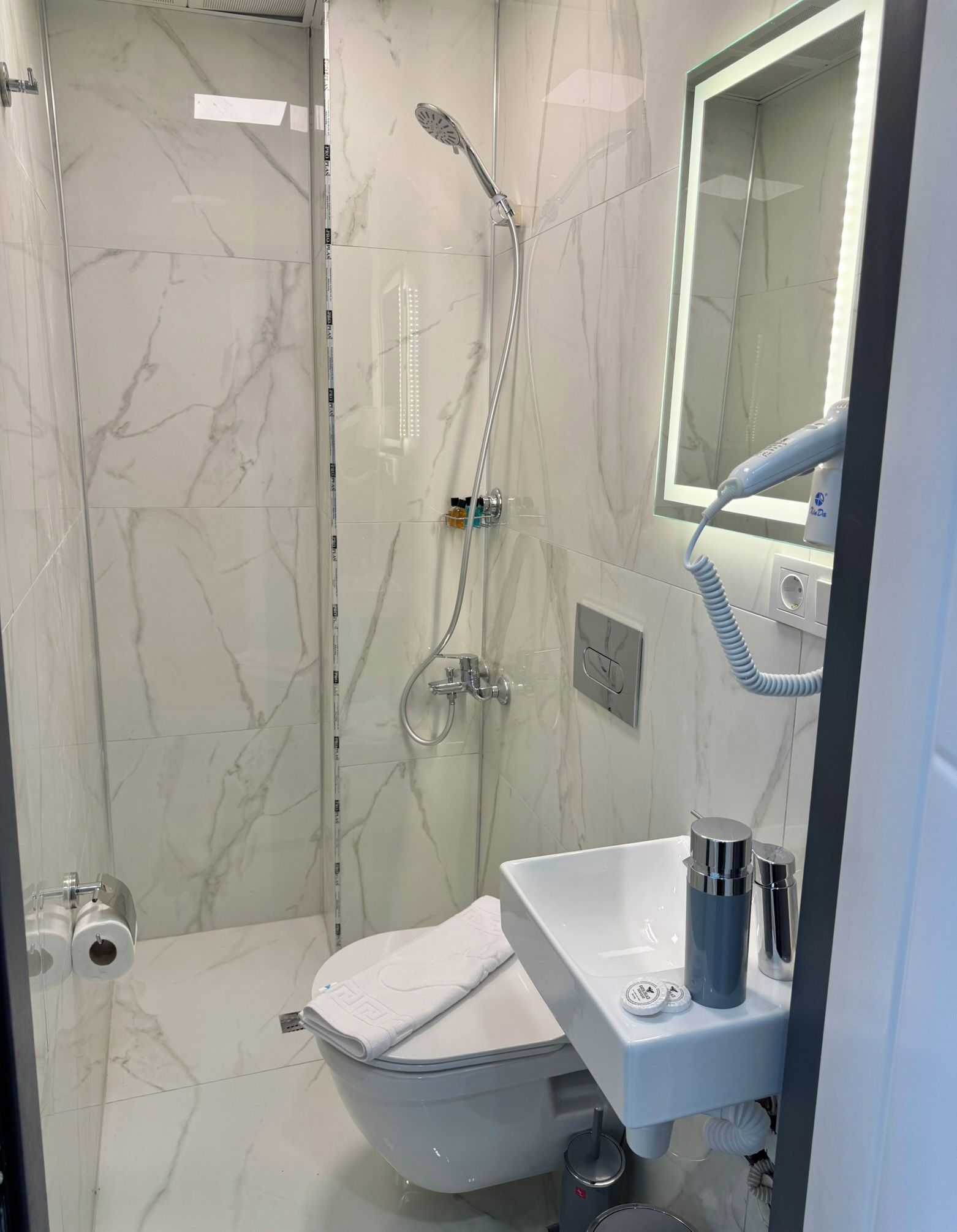 Ein Badezimmer mit Toilette, Waschbecken, Spiegel und Dusche.