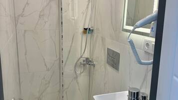 Ein Badezimmer mit Toilette, Waschbecken, Spiegel und Dusche.