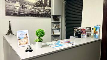 En receptionsdisk med en tavla, en liten krukväxt, en klocka och informationsbroschyrer.