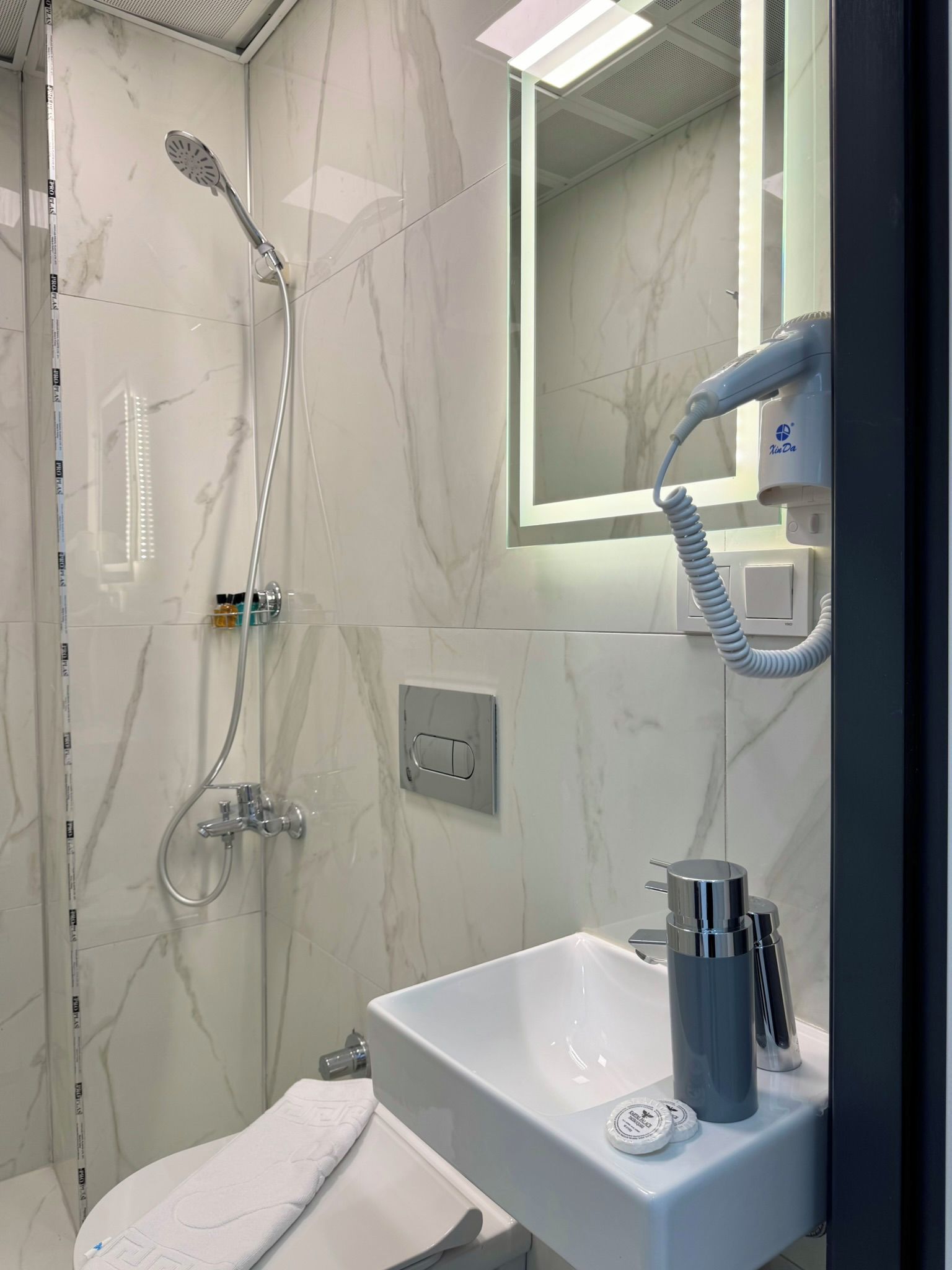 A modern bathroom with a shower, a sink, and a hairdryer.