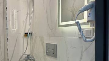 A modern bathroom with a shower, a sink, and a hairdryer.