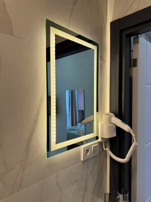 A bathroom with a vanity mirror, a hairdryer, and a towel rack. - NOVIVA HOTEL Taksim (Istanbul)