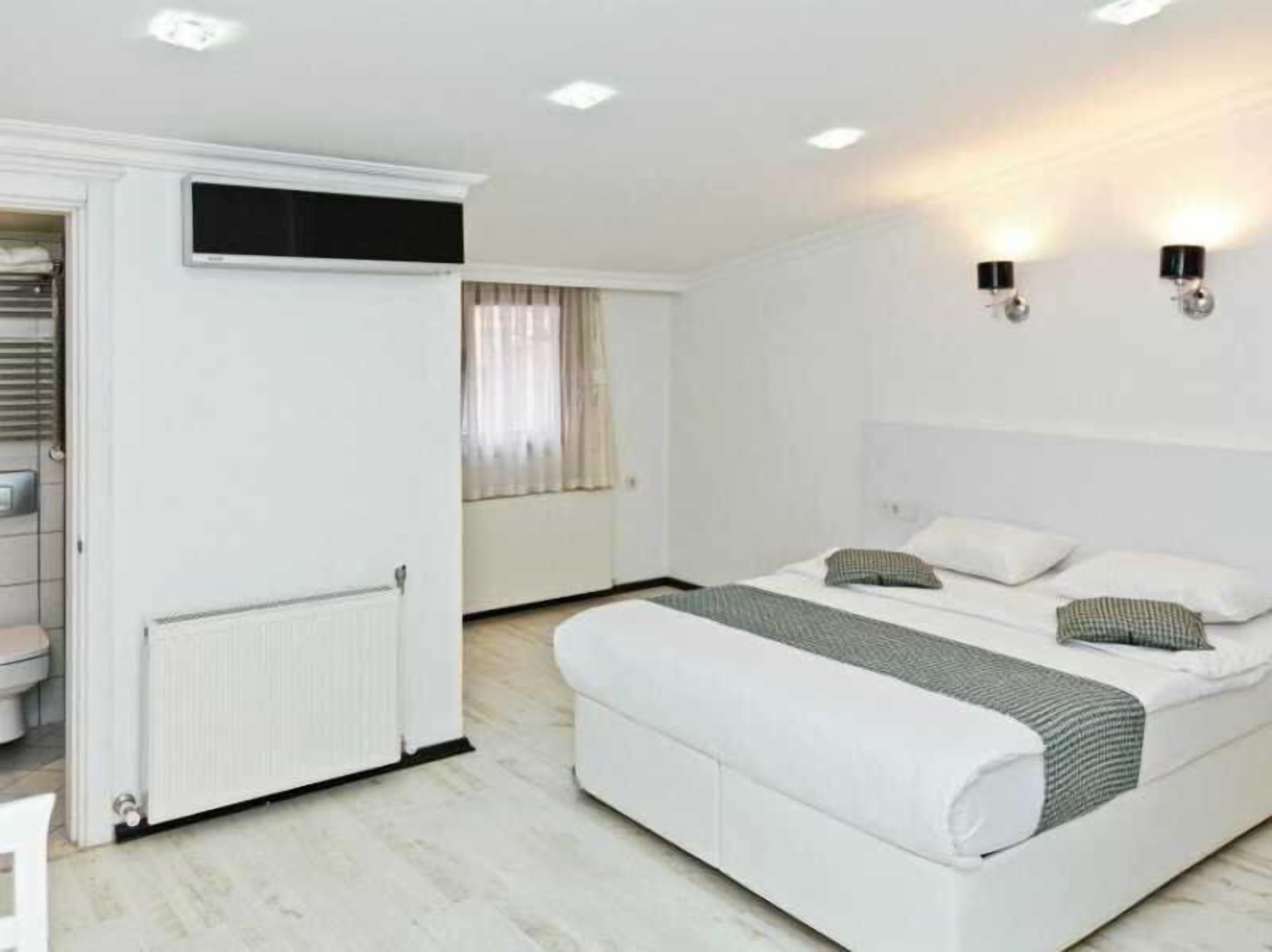 Ein Schlafzimmer mit einem Bett, einem Kleiderschrank, einem Heizkörper und zwei Wandleuchten.