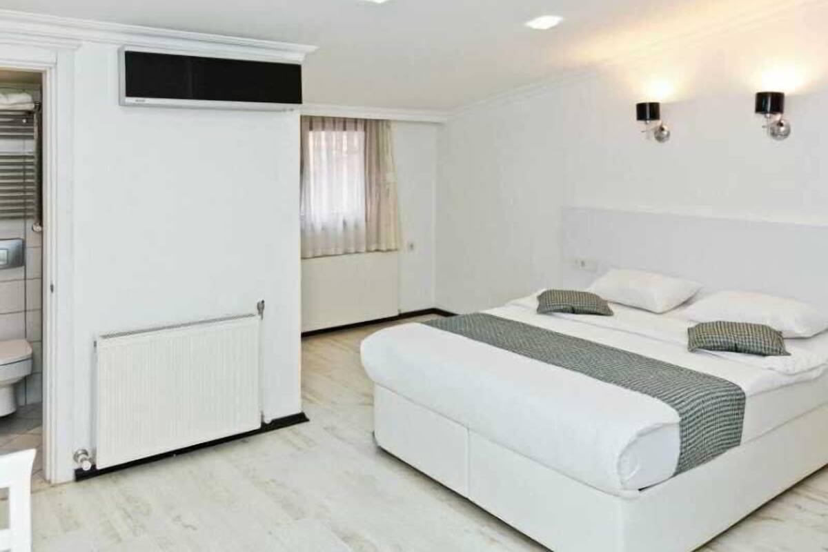 A bedroom with a bed, a wardrobe, a radiator, and two wall-mounted light fixtures.