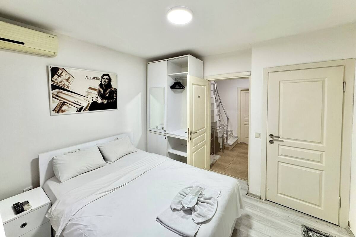 A hotel room with a bed, a nightstand, a wardrobe, and a door leading to another room.