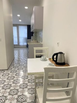 A narrow hallway with patterned floor tiles, a white table with a coffee maker, and a chair. - NOVIVA HOTEL Taksim (Istanbul)
