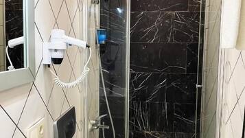 Ein modernes Badezimmer mit einer gläsernen Duschkabine, einem weißen Waschbecken und einem Spiegel.