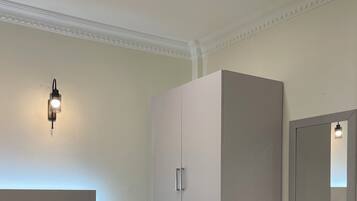 A bedroom with a bed, a wardrobe, a desk, and a mirror.