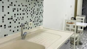 Een moderne keuken met een grote gootsteen, witte kastjes en een decoratieve spatwand.