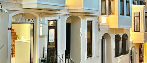A multi-story building with a well-lit entrance, a visible staircase, and a balcony on the upper floors.