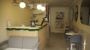 A cozy cafe with wicker furniture, a counter with a green garland, and a wall decorated with photos. - Alma Del Mar (Cartagena)