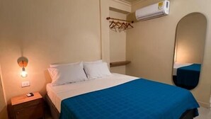 A bedroom with a bed, a nightstand, a wall-mounted air conditioner, and a mirror. - Alma Del Mar (Cartagena)