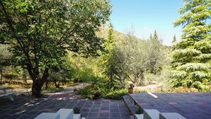 A paved garden area with a bench, surrounded by trees and shrubs. - Casa Calma Country Villa Escape with Private Pool (kato Pteri, Diakopto)