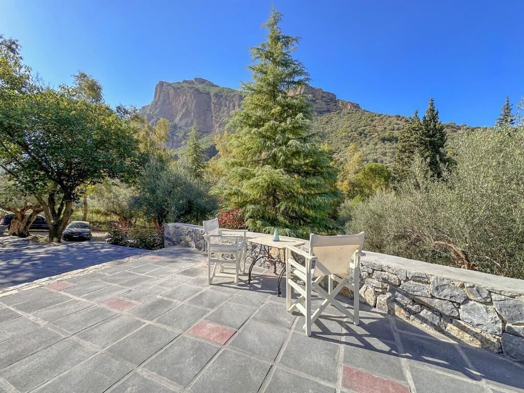 An outdoor patio area with stone flooring, a wooden fence, and a table with chairs.