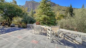 An outdoor patio area with stone flooring, a wooden fence, and a table with chairs. - Casa Calma Country Villa Escape with Private Pool (kato Pteri, Diakopto)