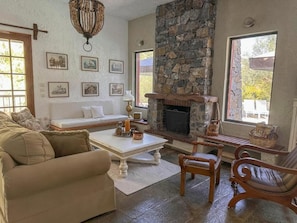 A cozy living room with a stone fireplace, a sofa, a coffee table, and a fireplace screen.