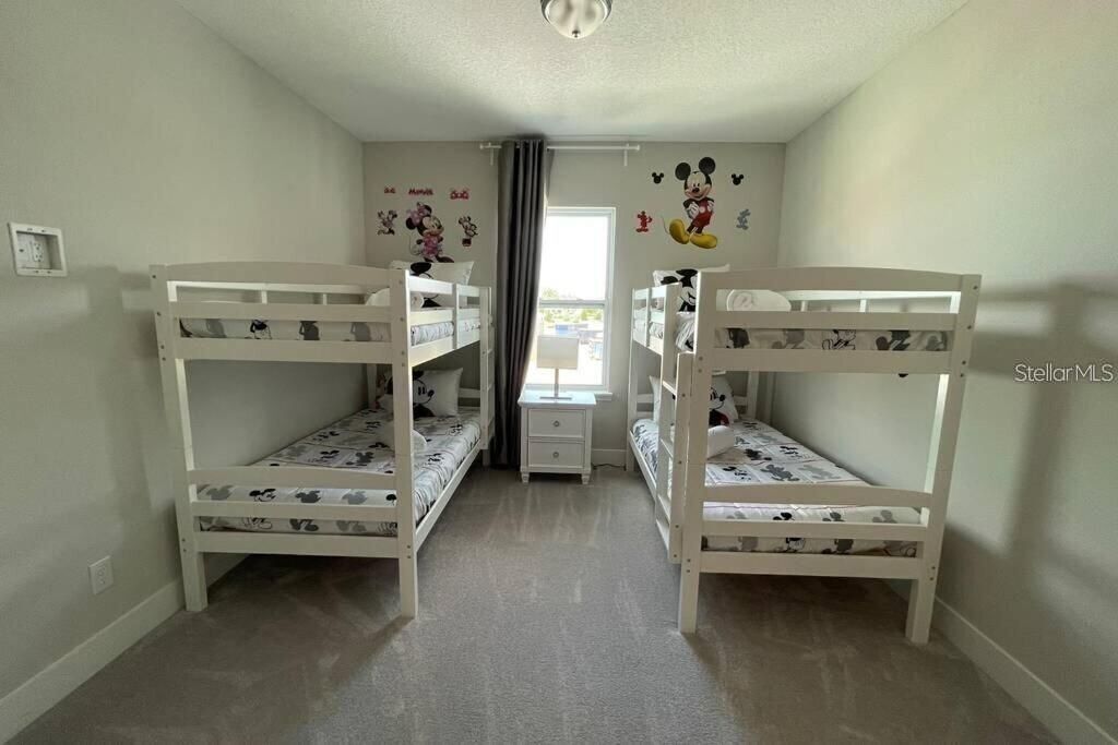 Ein Zimmer mit Etagenbetten, einem kleinen Schreibtisch und Wandbildern von Mickey Mouse.