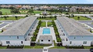 Un grand hôtel moderne doté d’une piscine centrale, de nombreux étages et d’une pelouse bien entretenue.
