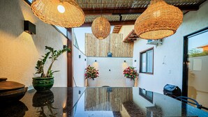 A modern kitchen with a glass-top island, hanging wicker pendant lights, and potted plants. - Casa DelMare Cond. com saída na praia (Buzios)
