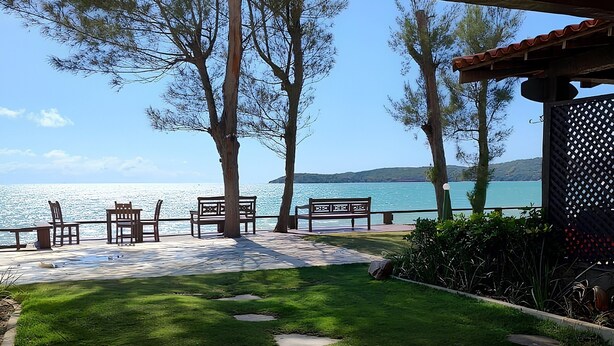 A patio with stone flooring, a grassy area, and wooden furniture. - Casa DelMare Cond. com saída na praia (Buzios)