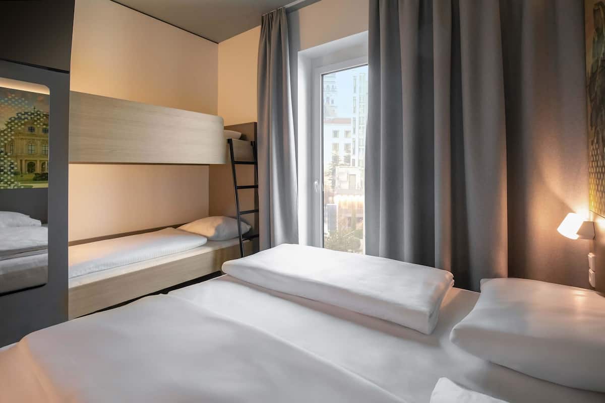 Ein Hotelzimmer mit Etagenbett, Schreibtisch und einem Fenster mit Vorhängen.