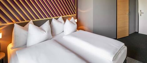A hotel room with a large bed, a wooden headboard, and a door.