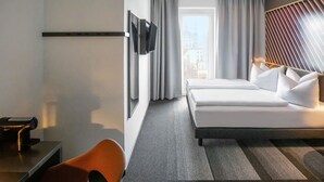 A hotel room with a bed, a desk, a chair, a TV, and a window with curtains. - B&B Hotel Würzburg-Altstadt (Würzburg)