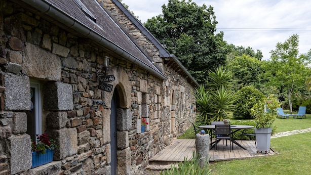 A stone building with a wooden deck, outdoor seating, and potted plants.