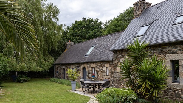 A stone house with a tiled roof, a stone pathway, and a garden with a table and chairs. - Guesthouse 'Chambre Marine' with Shared Terrace, Garden and Wi-Fi (Lannion)