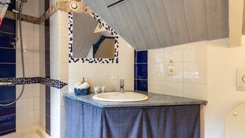 Een badkamer met een douche, een wastafel, een spiegel en een handdoekhouder.