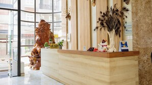 Zona reception di un hotel con una scrivania in legno, teste di animali appese e un'ampia vetrata che dà sull'esterno.