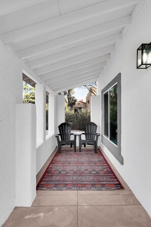 Une terrasse couverte avec deux chaises, un tapis à motifs et une vue sur les environs.