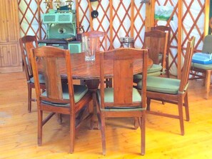 Una mesa de comedor de madera con sillas, una radio antigua y un cuadro en la pared.